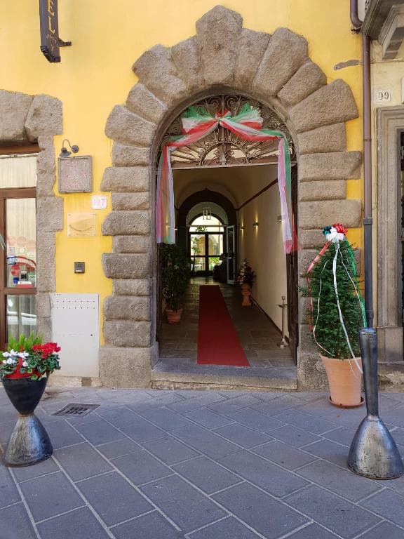Hotel entrance with stone archway, Italian flag colors, and red carpet leading inside