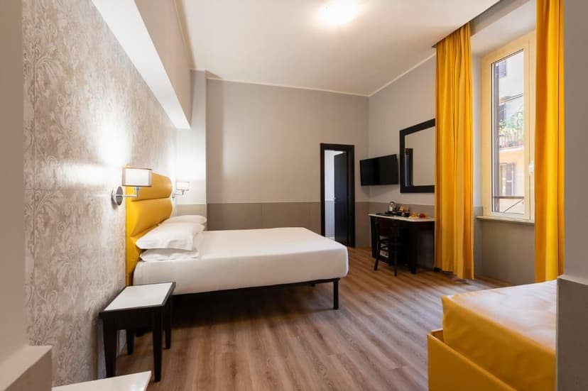 Hotel room with white bedding, yellow headboard, wood floor, and bright yellow curtains.