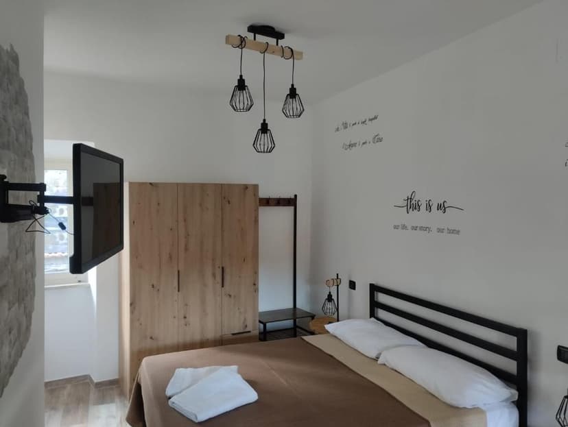 Bedroom with modern black metal bed, wood wardrobe, and "this is us" wall decal