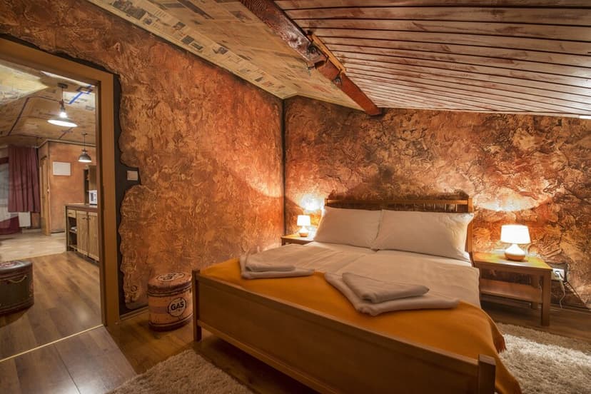 Cozy bedroom with textured orange walls, wooden bed, and lamps, near Poprad.