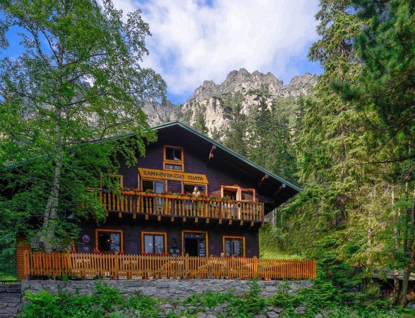 Zamkovského Chata wooden mountain hut surrounded by forest with rocky peaks overhead