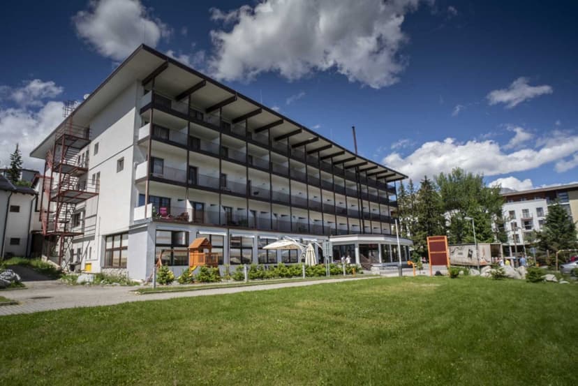 Hotel Toliar at Štrbské Pleso with balconies, green lawn, and blue sky.