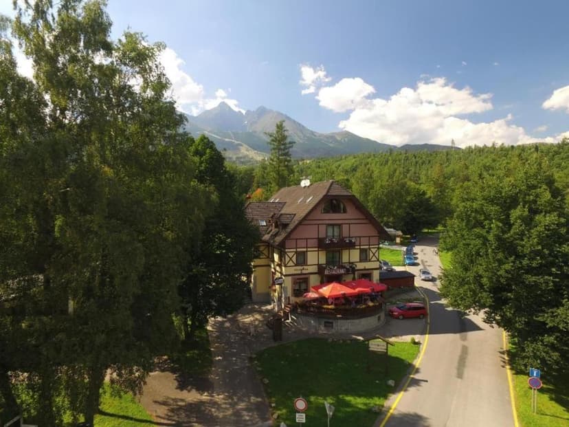 Restaurant building with outdoor seating near mountains and dense forest in Vila Park Lomnica