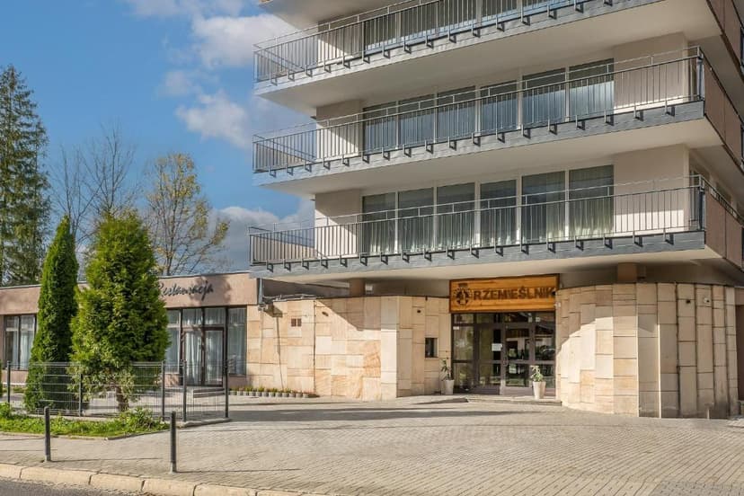 Hotel Rzemieślnik entrance with stone facade, balconies, and restaurant sign in Zakopane.