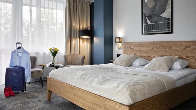 Hotel Rzemieślnik Zakopane hotel room with wooden bed, blue suitcase, and natural light.