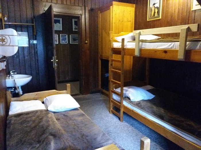Bunk beds and single beds in a rustic wooden room at Morskie Oko hut.