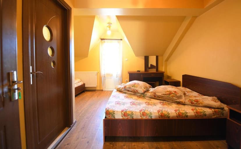 Attic guest room with floral bedding, wooden floor, and bright window light.