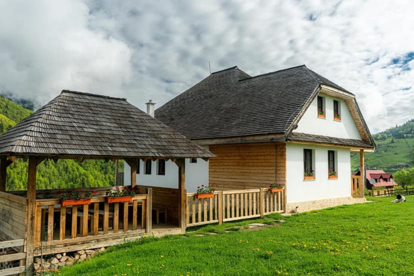 Wooden pension building with shingled roof and covered porch in green mountain setting