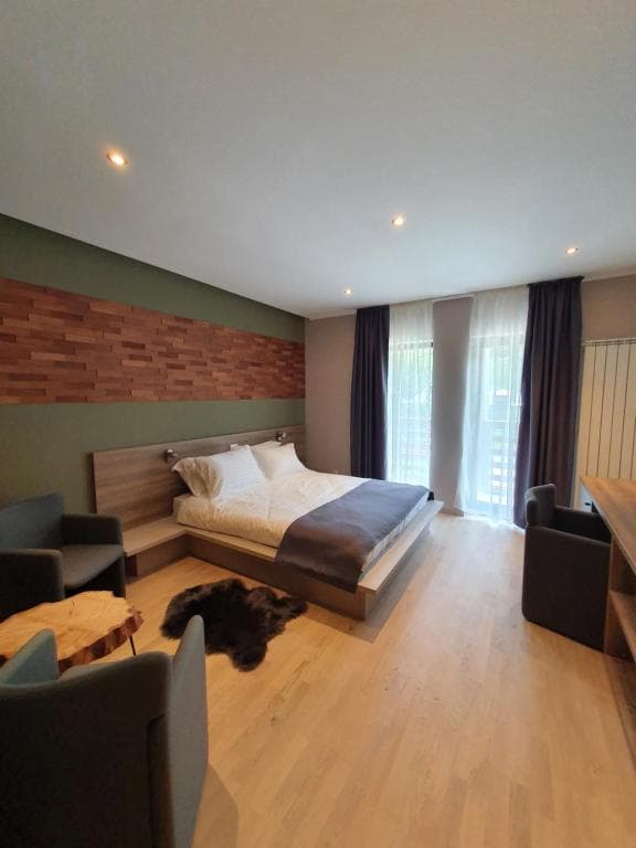 Modern guesthouse room with wooden floor, platform bed, and seating area.