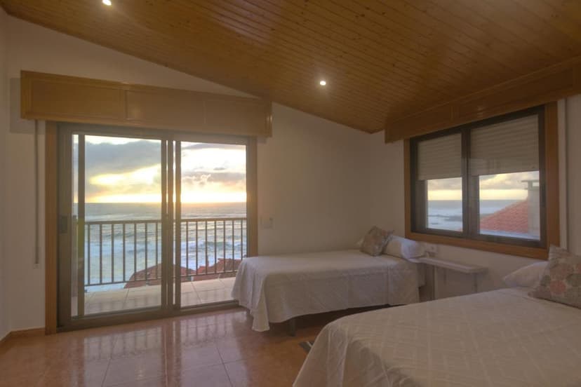 Bedroom with twin beds overlooking ocean sunset through sliding glass doors