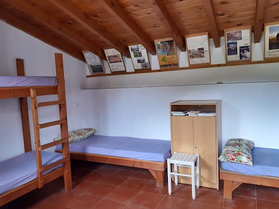 Bunk beds and single beds with purple mattresses in Albergue de Peregrinos de Güemes dormitory room.