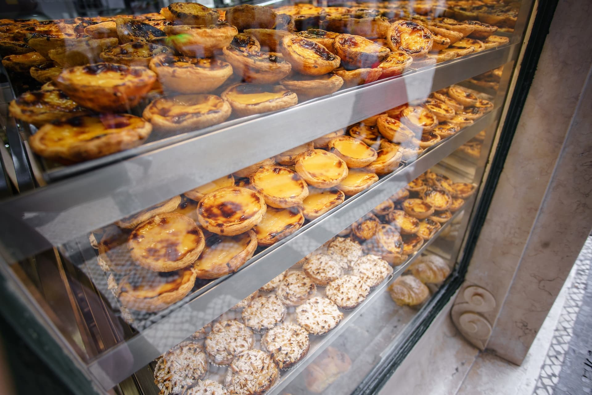 Pastéis de nata and coconut pastries displayed in a bakery window case