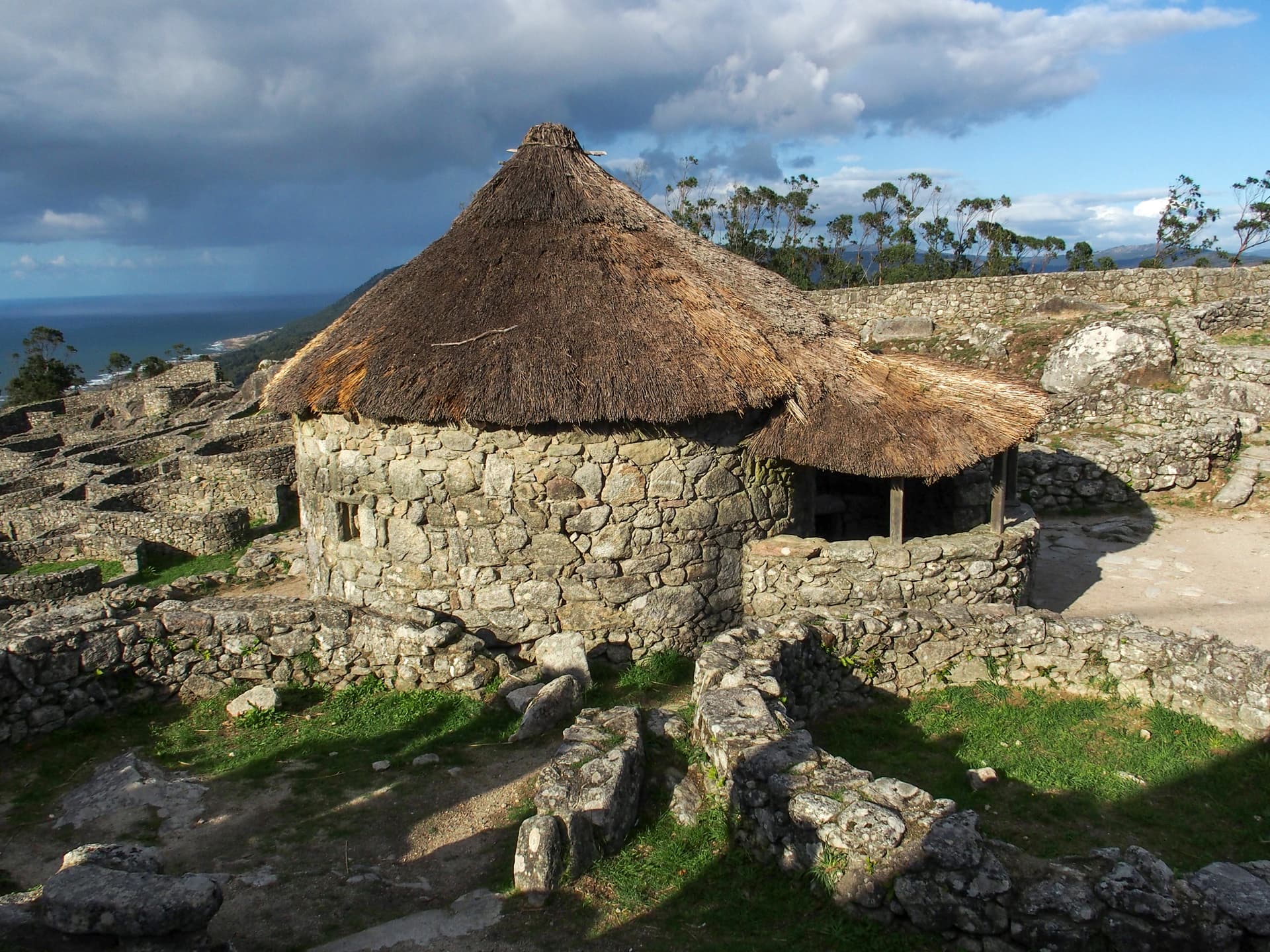 Stone hut with thatched roof at Monte Santa Trega ruins overlooking the sea.