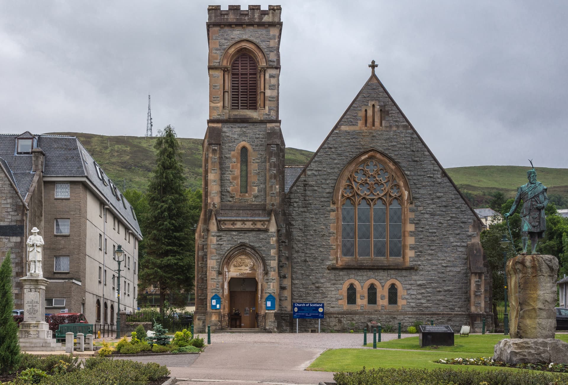 Stone Church of Scotland with tower, statue, and green hill in Fort William.