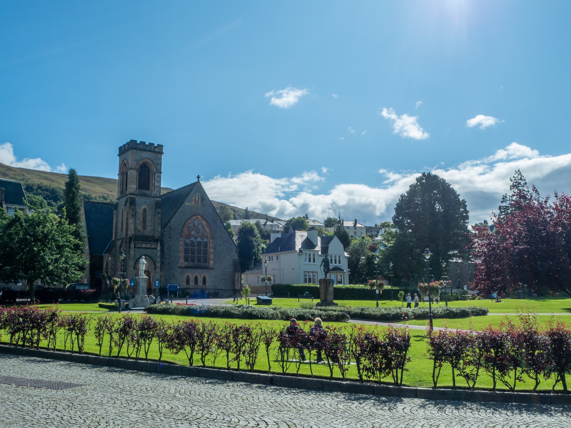 Stone church next to park with green grass and hills in Fort William, Scotland.