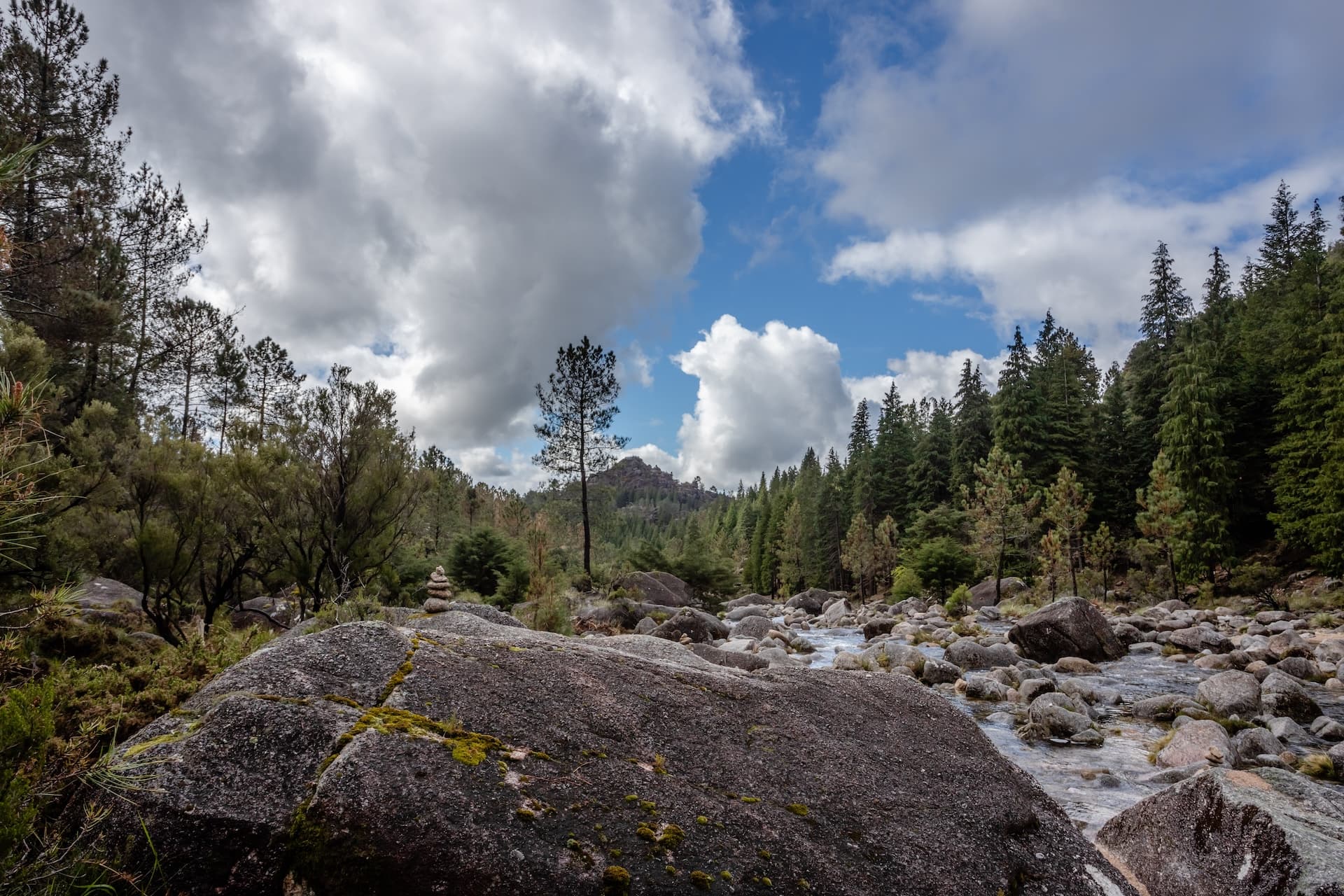 Mountain creek flowing over rocks in Peneda-Geres, Portugal under cloudy sky.