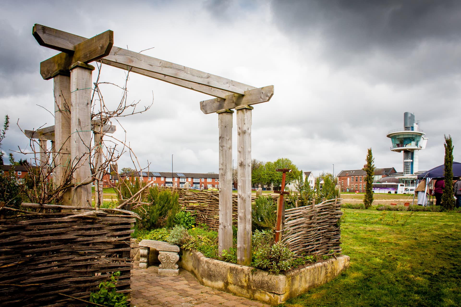 Wooden pergola structure in a garden with a modern observation tower in the background, Wallsend.
