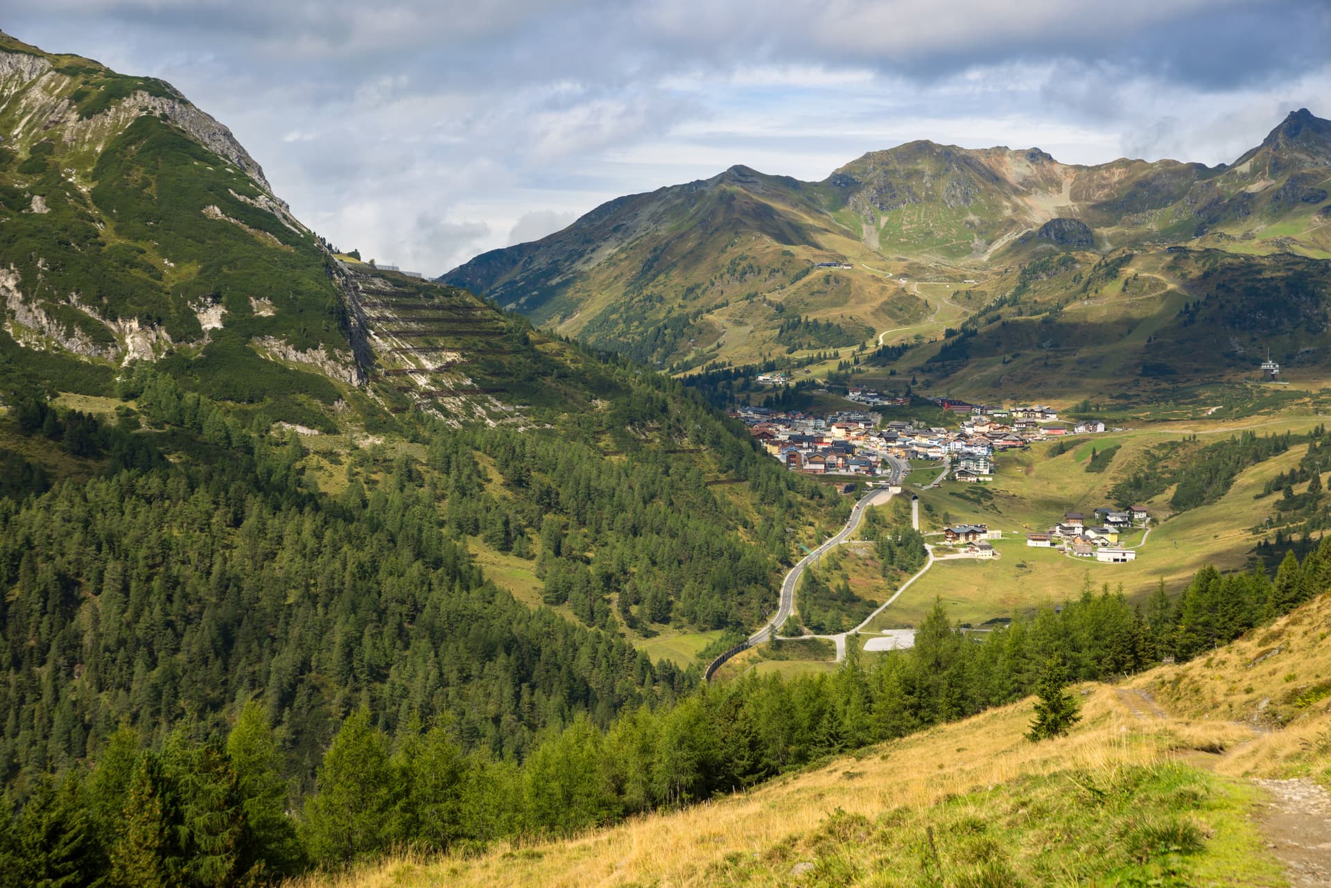 Alpine village nestled in a green valley surrounded by steep mountains under a cloudy sky in Obertauern.