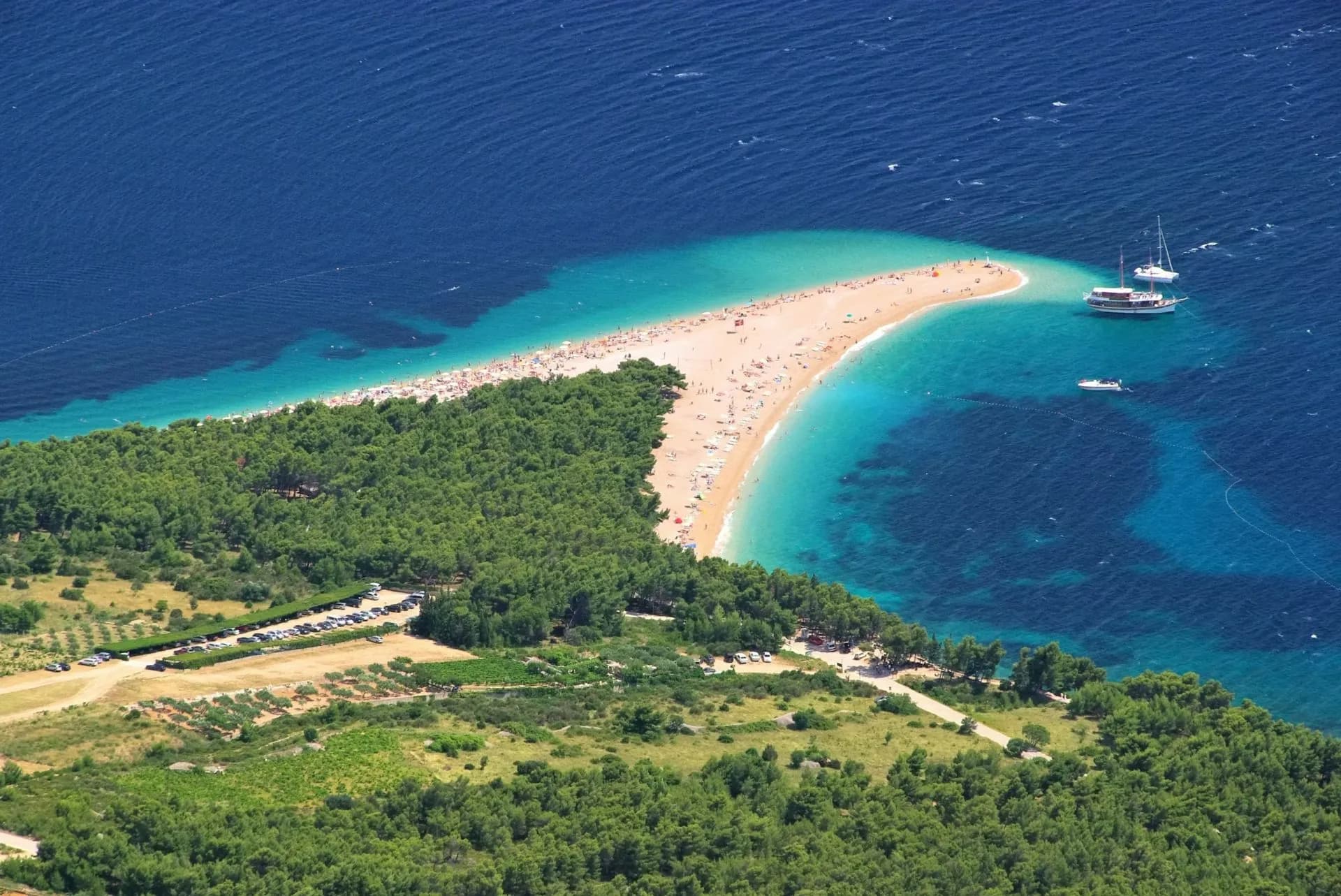 Zlatni Rat beach in Bol, a white pebble spit extending into turquoise Adriatic Sea with boats.