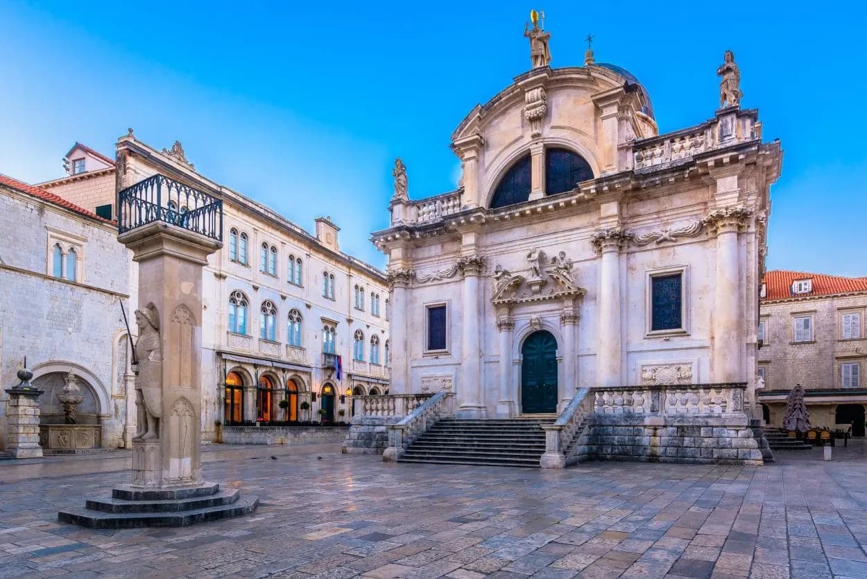 Baroque church and stone column in the empty square of Dubrovnik's old town.