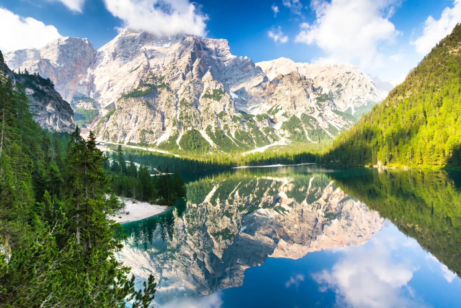 Lago di Braies with towering mountains reflected in the calm alpine lake water.