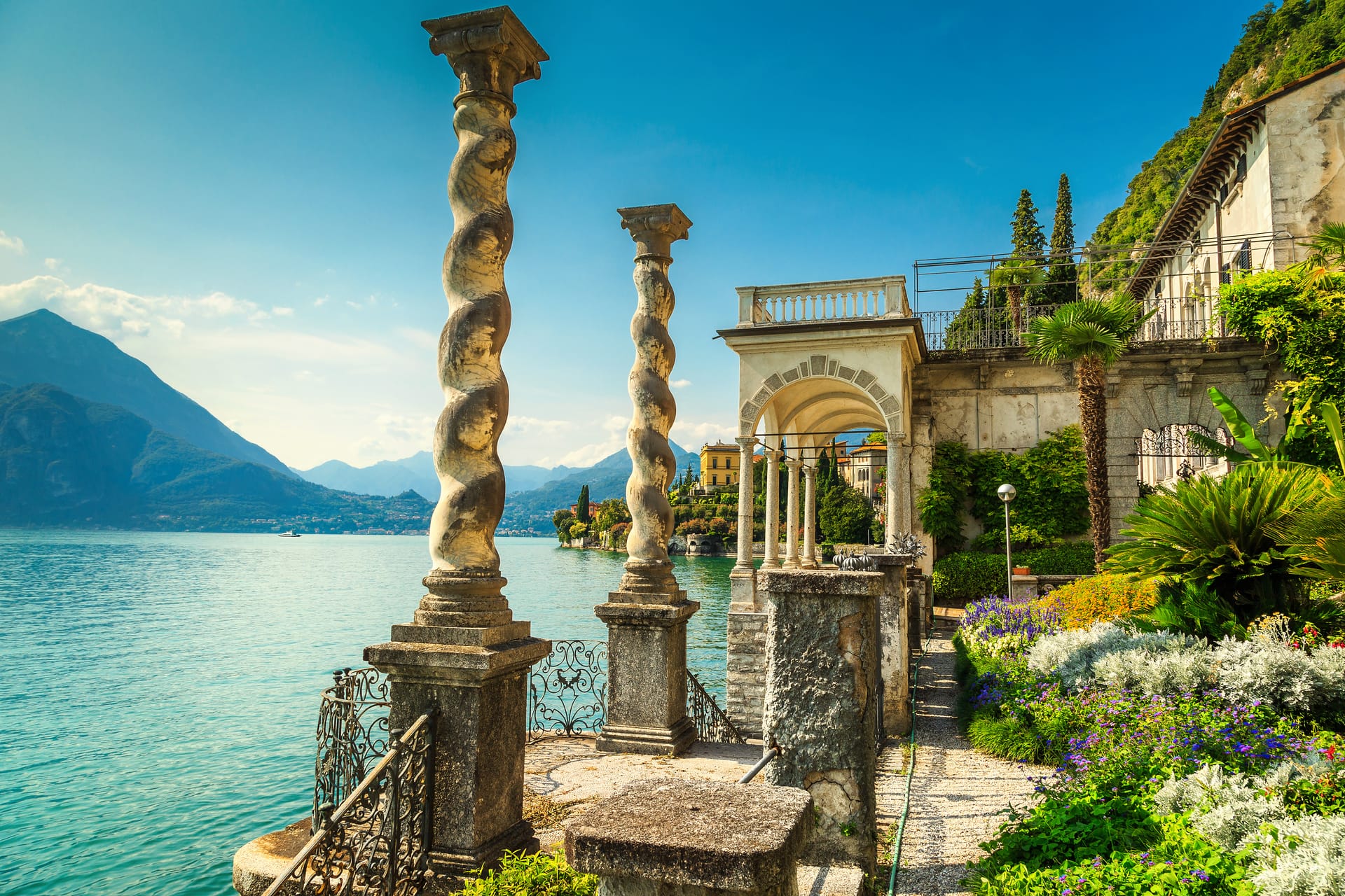 Stone terrace with ornate columns overlooking turquoise lake and lush mountains