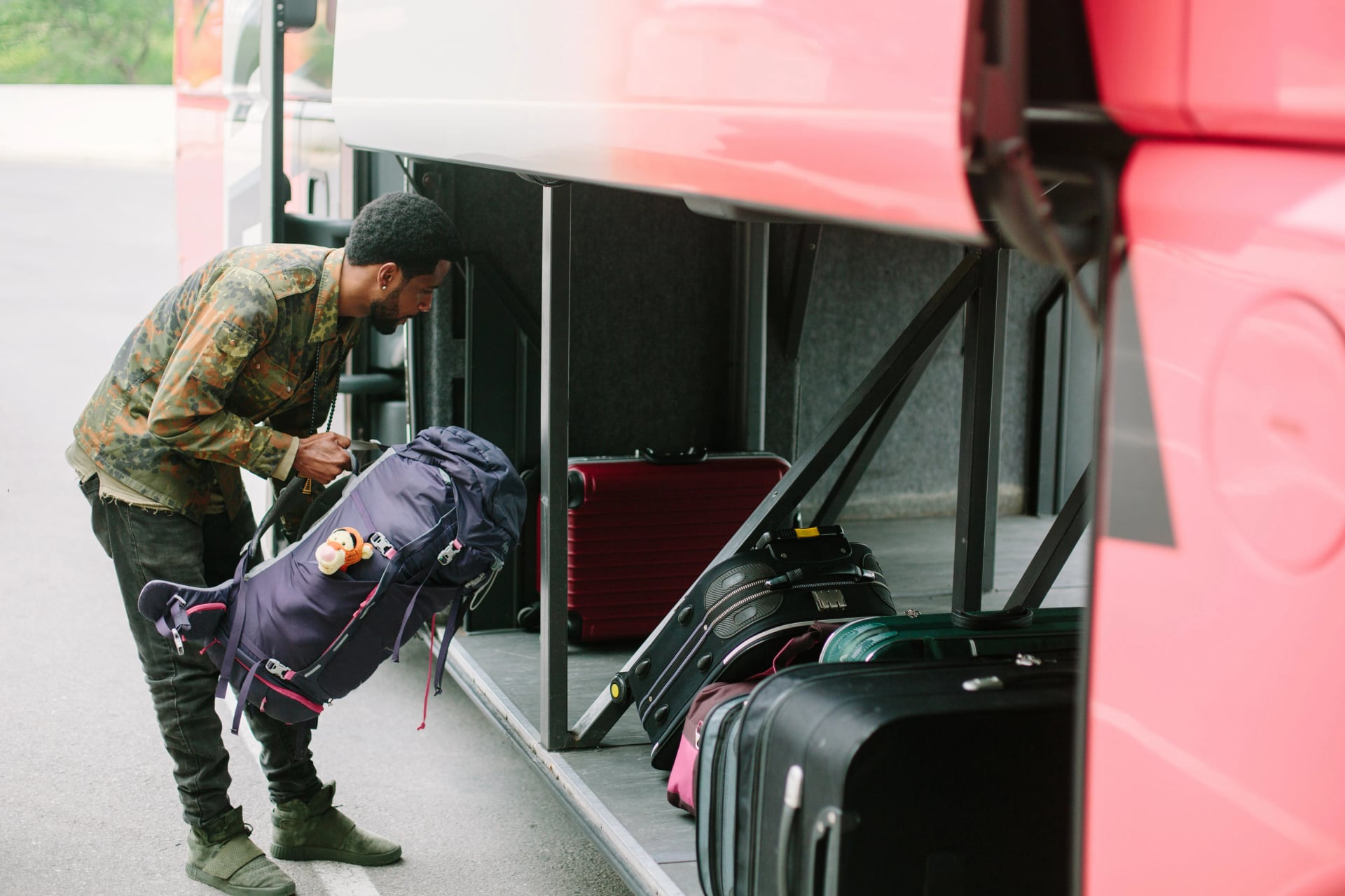 Traveler man put backpack to tourist bus luggage place