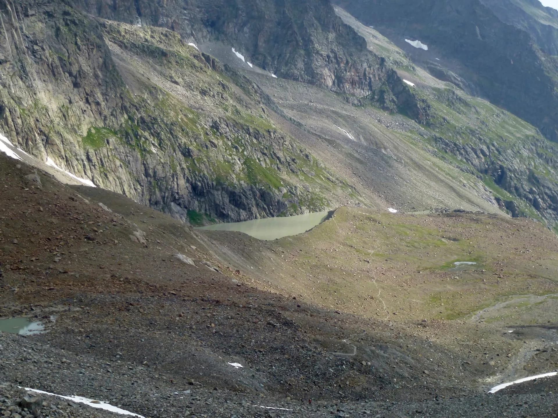 Alpine landscape with rocky slopes, small glacial lakes, and patches of snow near Stubai Path.