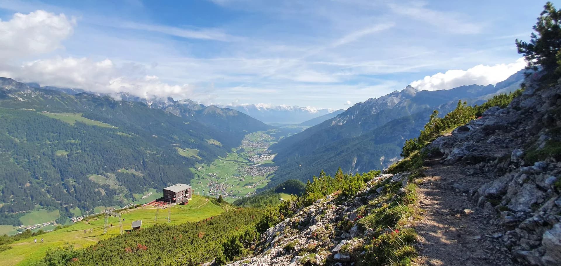 Hiking trail above Elferhütte overlooking Stubai Valley with alpine village below.