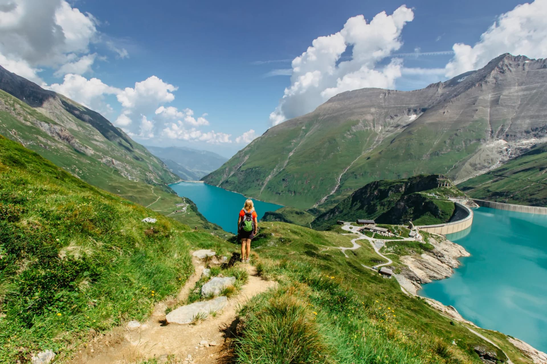 Beautiful scenic view of high mountain lakes.Girl hiking to the Mooserboden dam in Austrian Alps.Active sporty lifestyle.Wonderful nature landscape,turquoise tranquil water,holiday travel scene