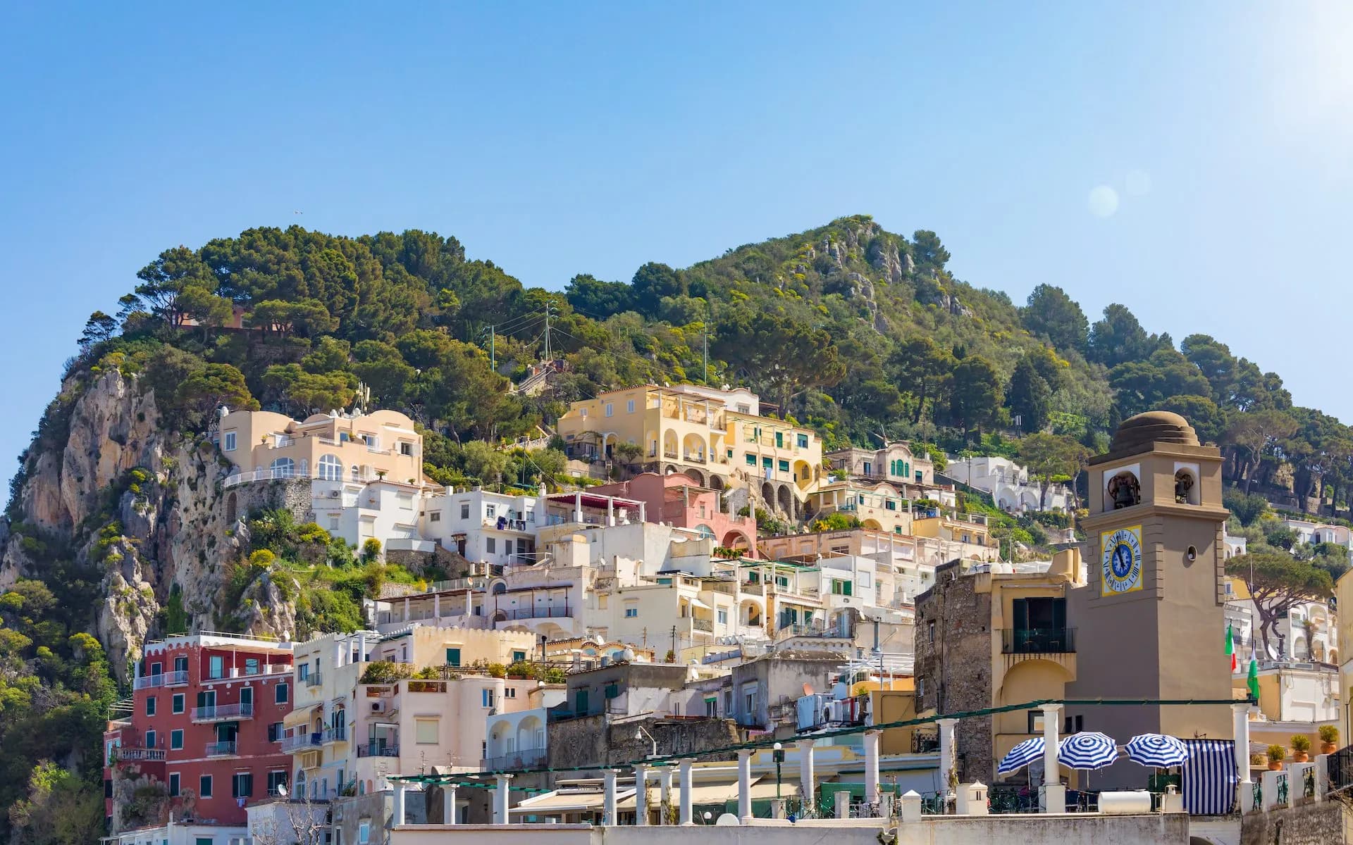 Daylight view of colorful buildings climbing a hillside near the clock tower in La Piazzetta, Capri Island.