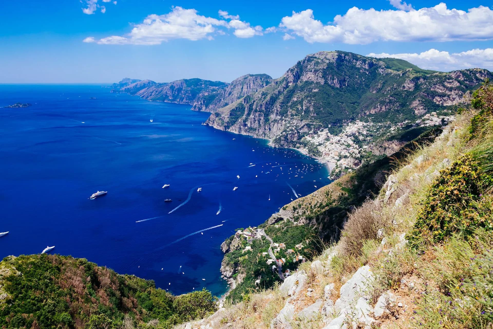 Hiking view of Positano and Amalfi Coast from Sentiero degli Dei with boats on blue sea.