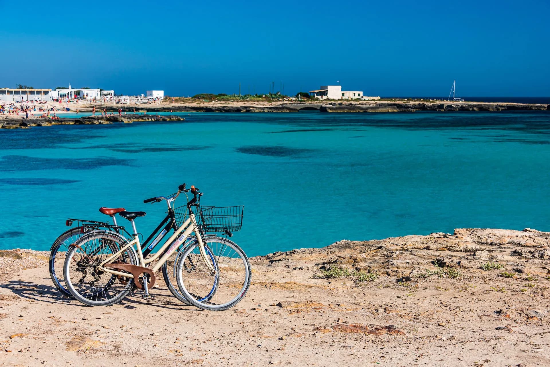 Two bicycles parked on rocky shore overlooking turquoise Mediterranean sea near Favignana.