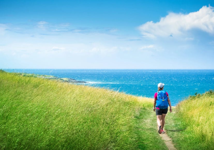 girl with backpack travels along sea coast along Camino de Santiago
