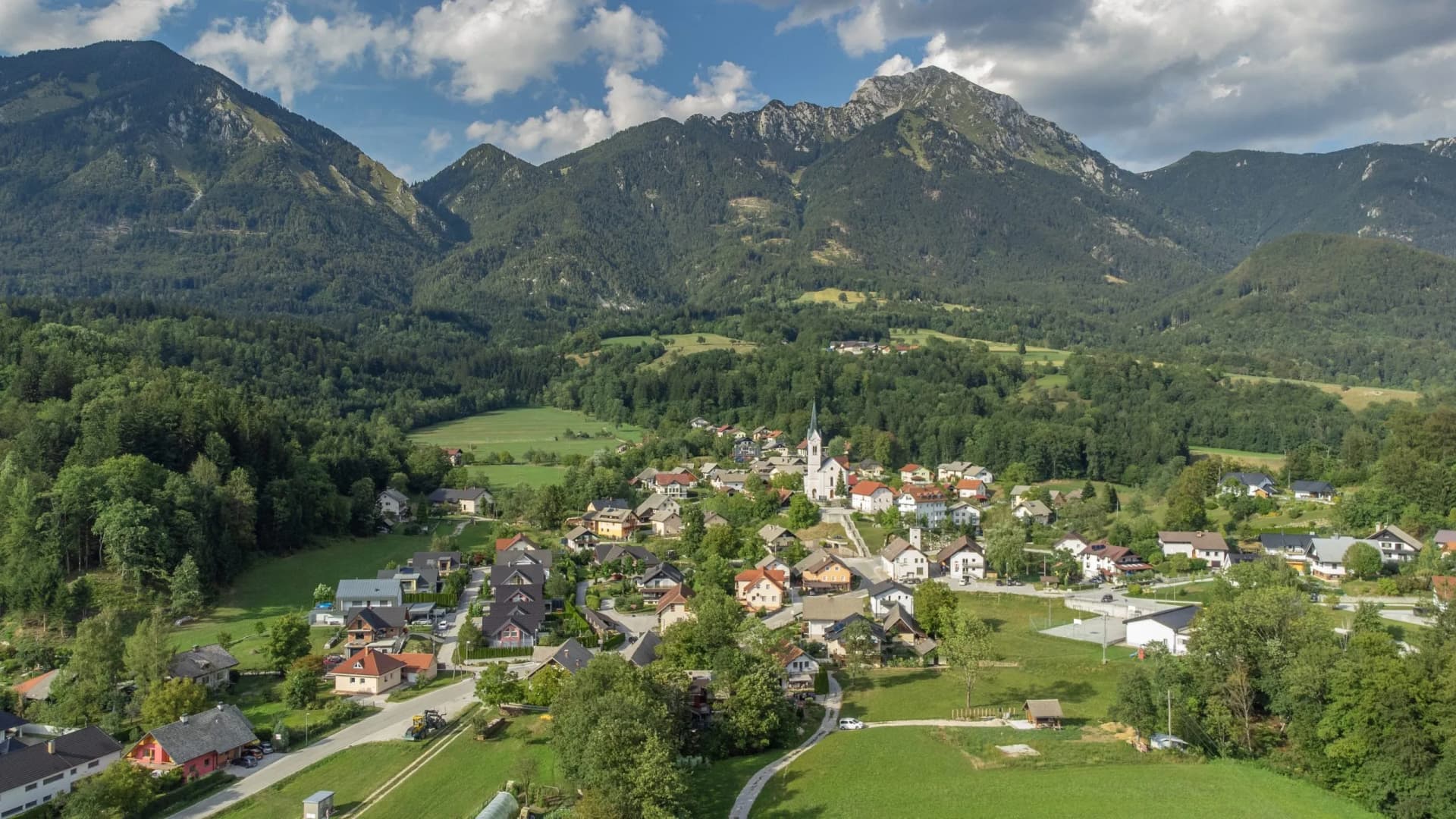 Village nestled in green valley below forested mountains above Trstenik.
