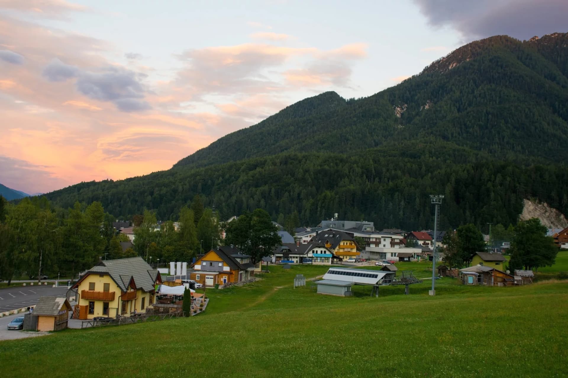 Alpine village of Kranjska Gora nestled against a steep, forested mountain at sunset