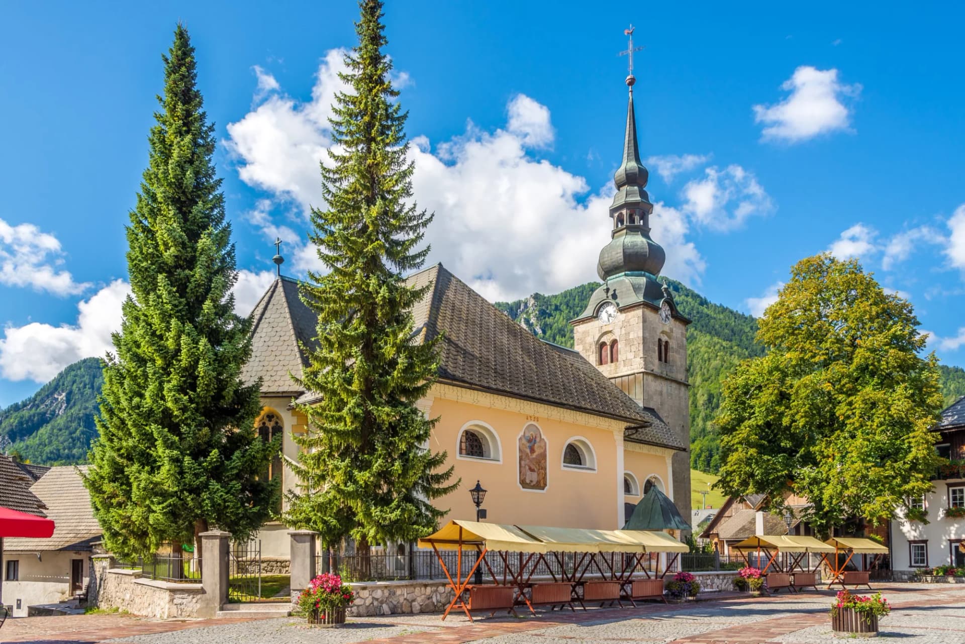 Church of Our Lady on the White Gravel in Kranjska Gora with tall pines and mountains.
