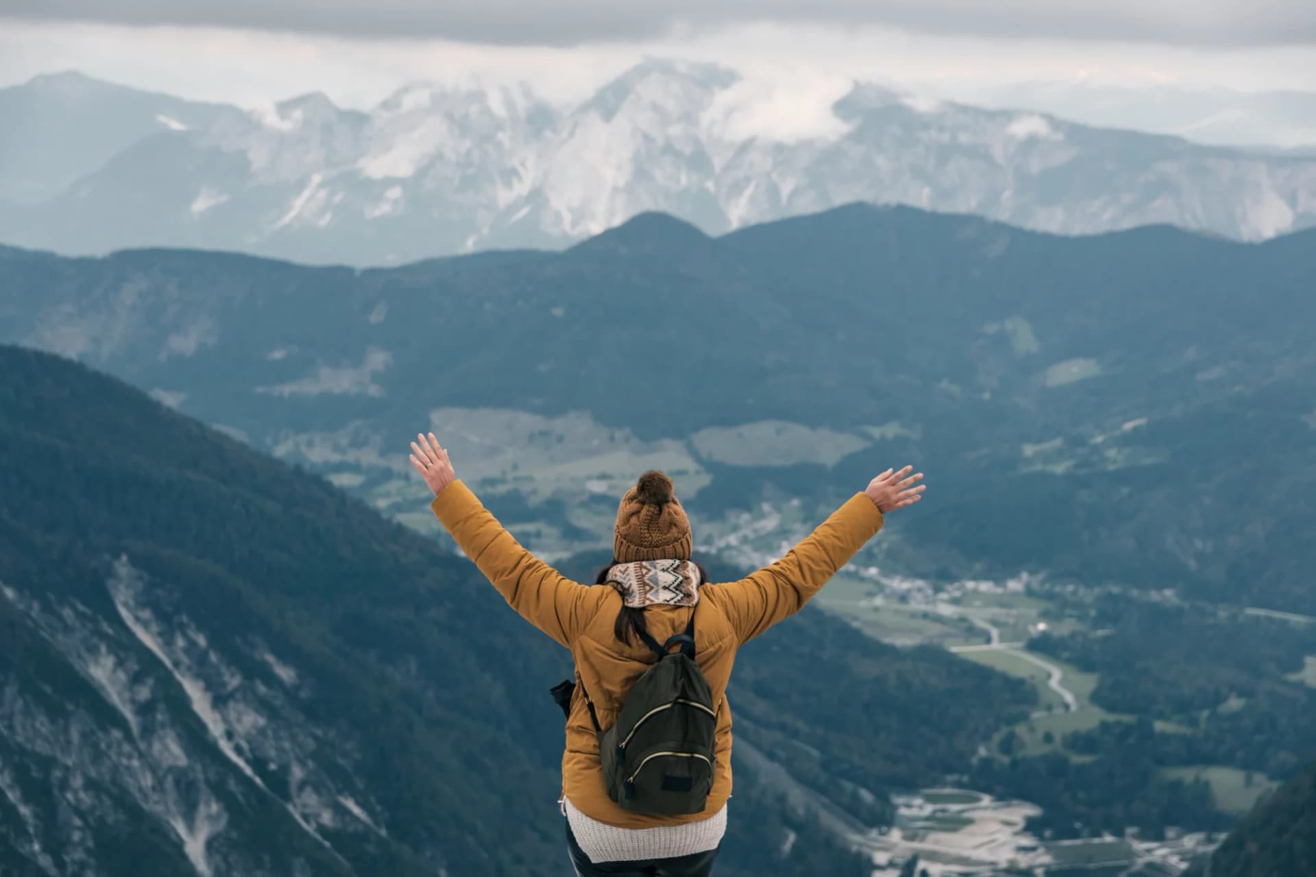 Hiker with outstretched arms overlooking Slemenova Špica in the Julian Alps.