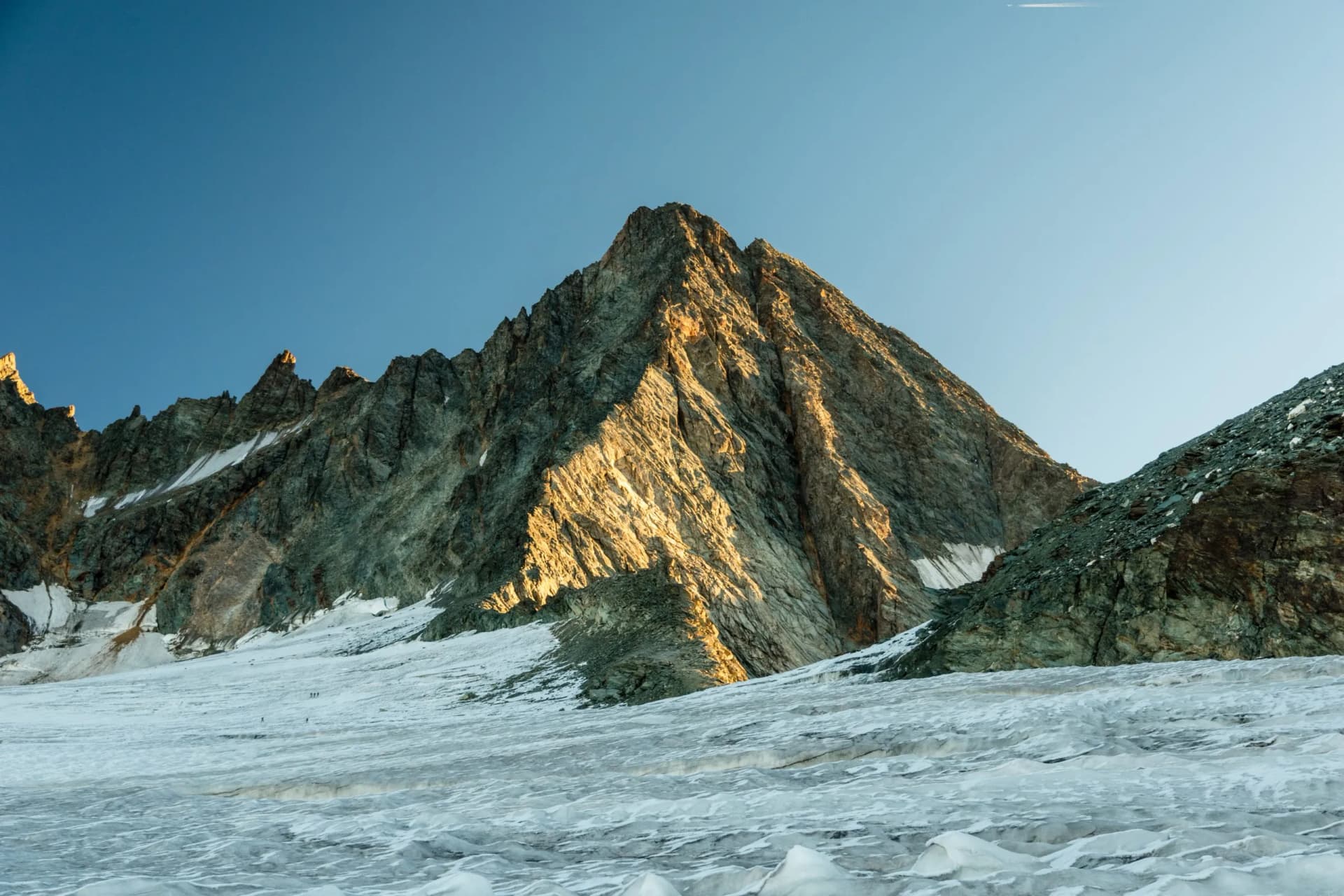 Glacier hiking toward Grossglockner peak via Studlgrat with small figures on ice.
