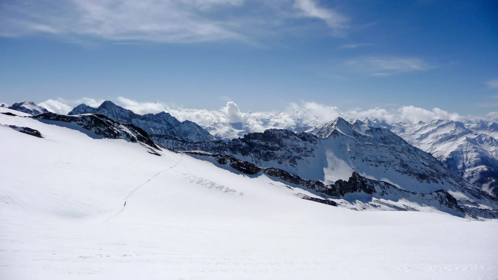 winter moutnain landscape in the Austrian Alps with many backcountry skiers crossing a large glacier and a great background view