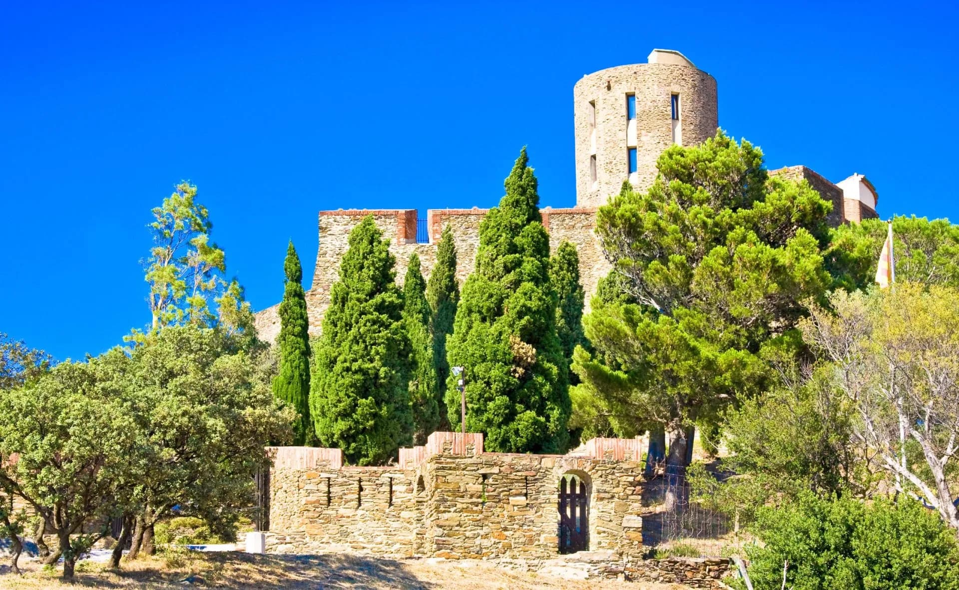 Fort Saint-Elme between Port-Vendres and Collioure with cypress trees under a bright blue sky.
