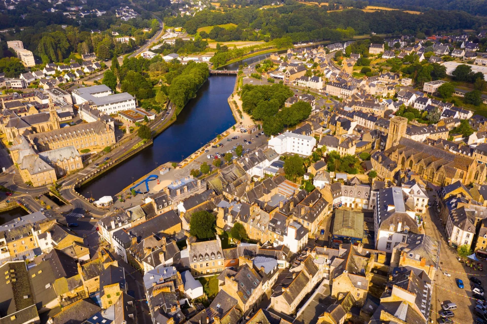 Aerial view of Lannion town center with dense stone buildings and a river winding through the landscape.
