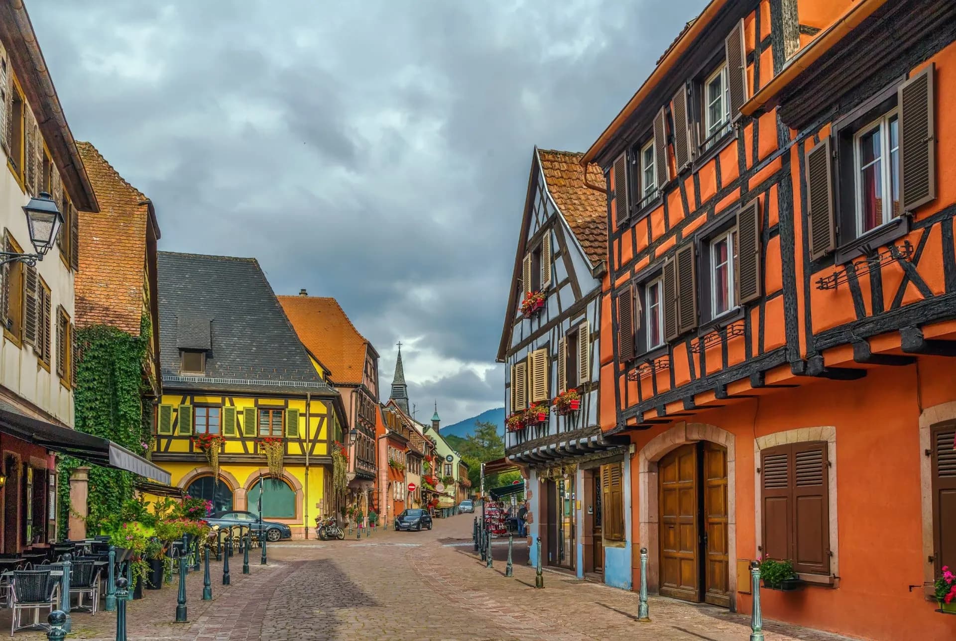 Cobblestone street lined with colorful half-timbered buildings in a French village.