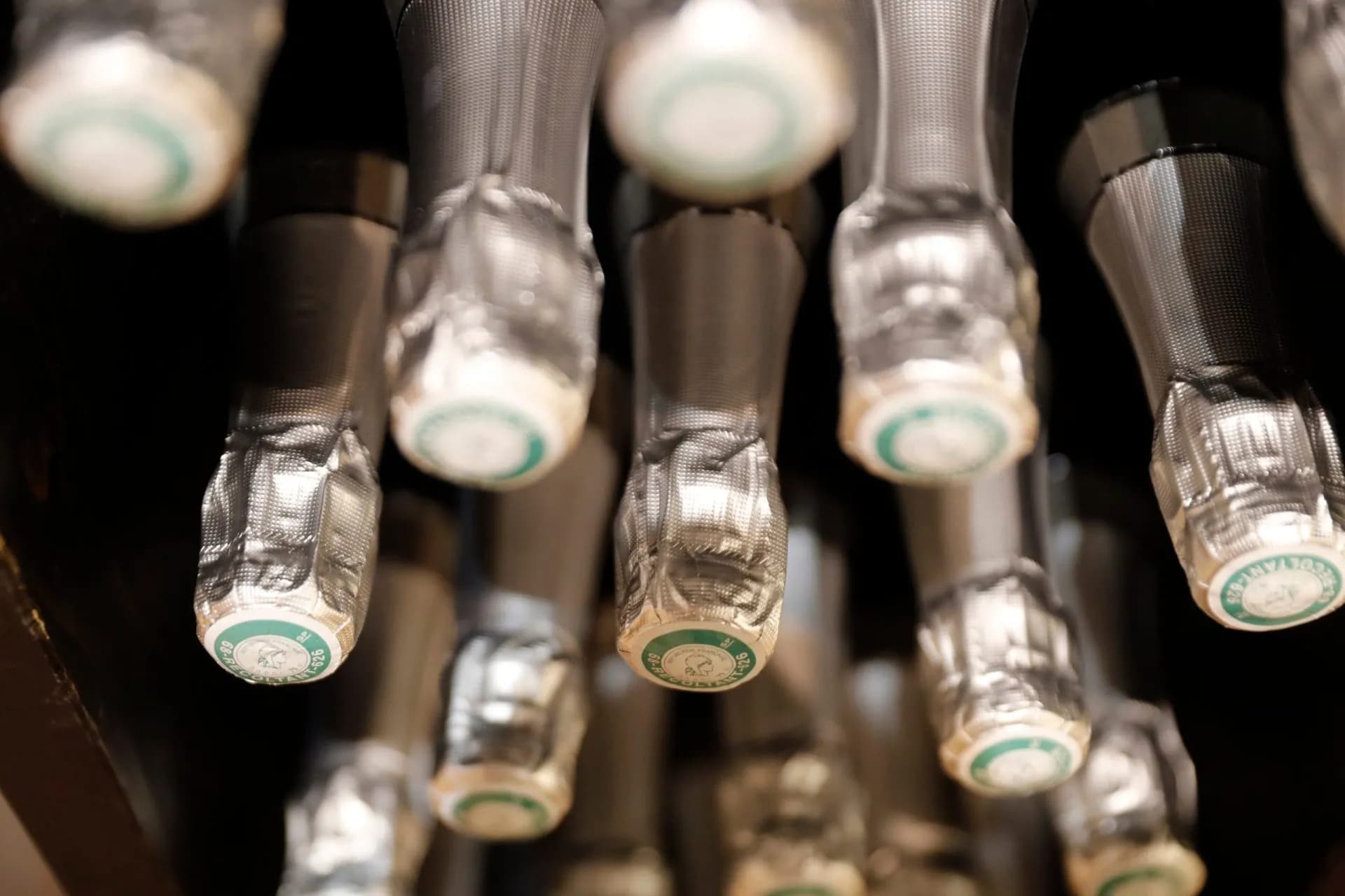Champagne bottle foils and green-labeled cork tops stored upside down in a cellar.