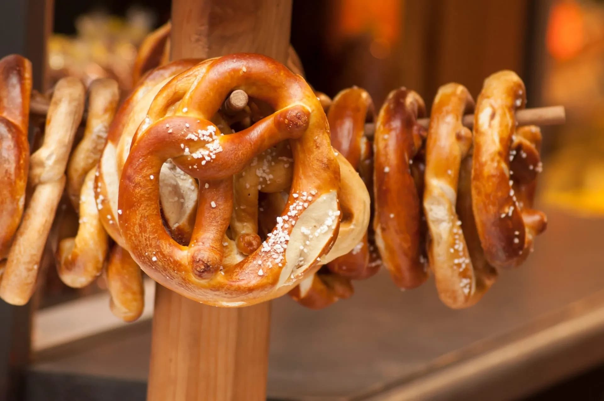 Traditional Alsatian pretzels salted and hanging on a wooden display pole.
