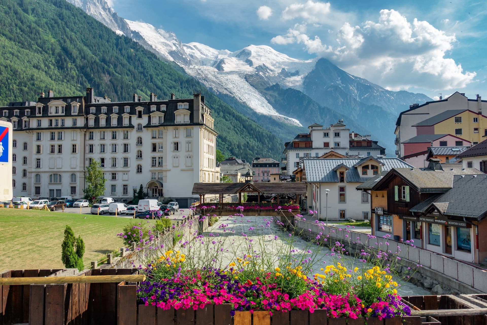Chamonix town with river, flowers, and glacier-capped mountains in background