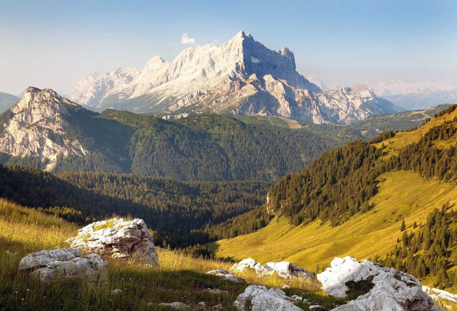 Rocky foreground overlooking forested slopes and massive pale mountain peaks, Monte Civetta.