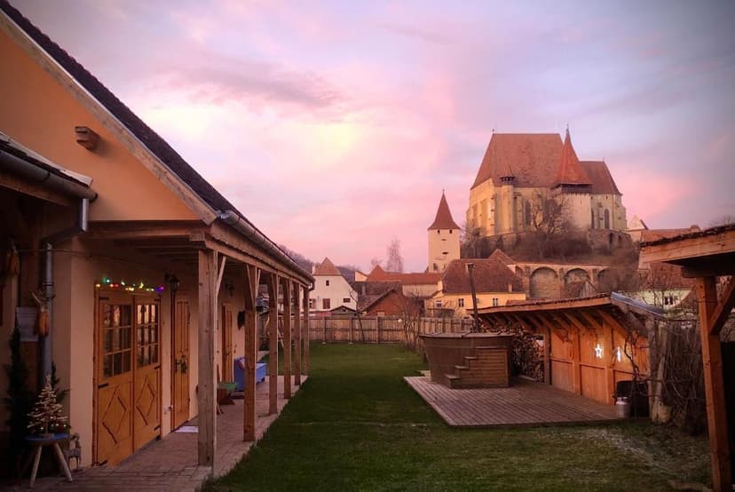 Courtyard with wooden hot tub and fortified church on hill at sunset, Casa Eva Wagner