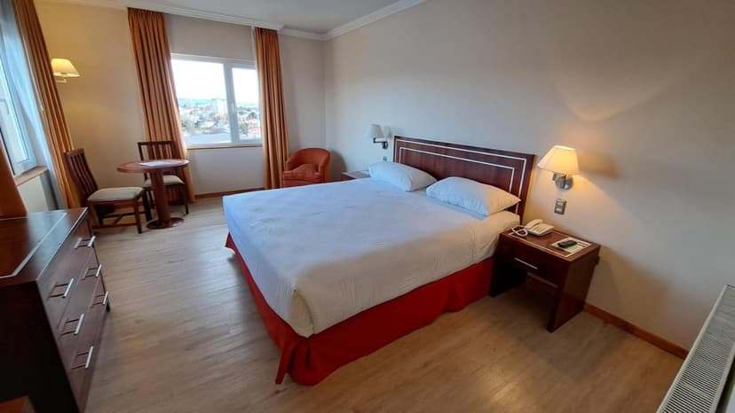 Hotel Diego de Almagro Punta Arenas room with double bed, wooden furniture, and city view.