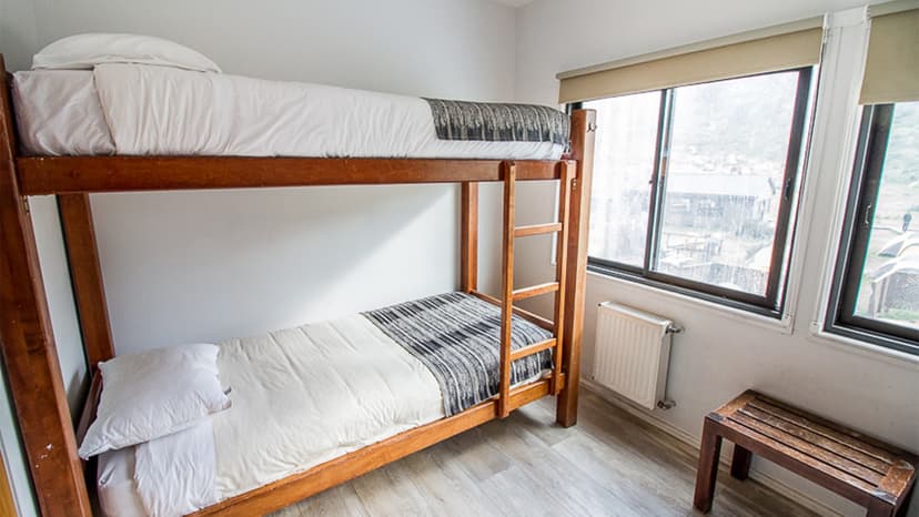 Bunk beds with white bedding in a room overlooking a valley near Pehoe Lake.